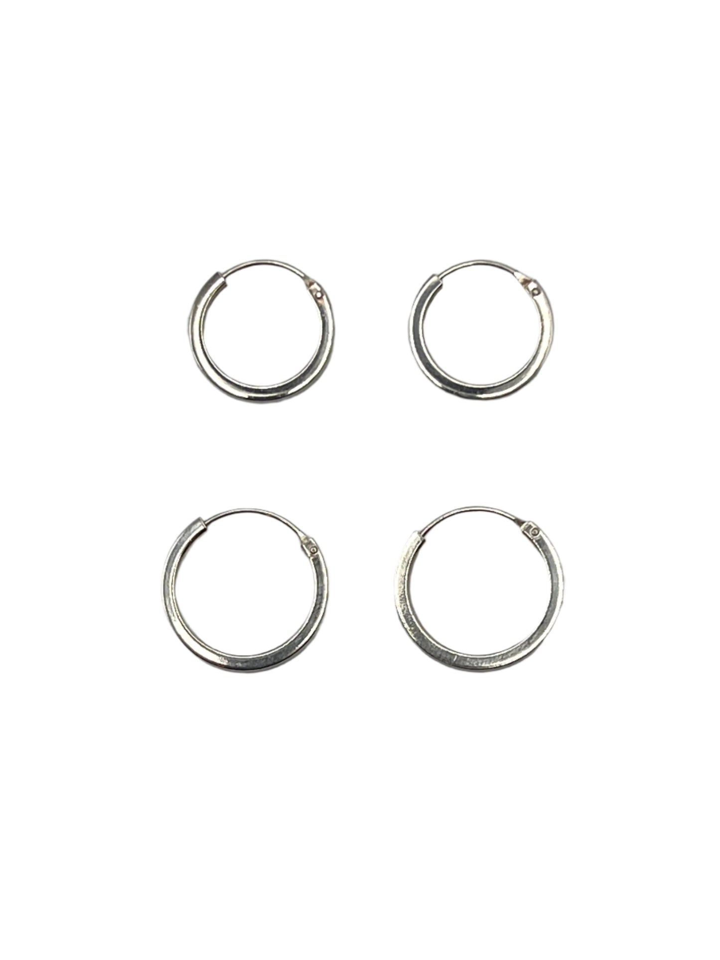 Four silver hoop earrings on a gray background