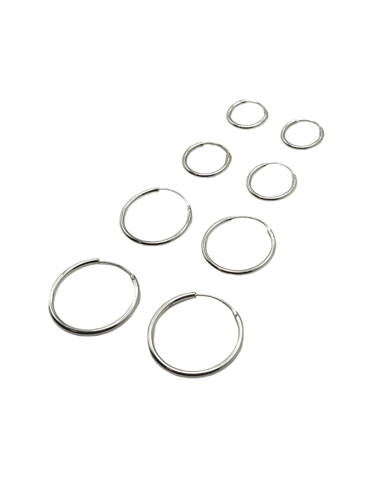 Set of silver hoop earrings on a light gray background