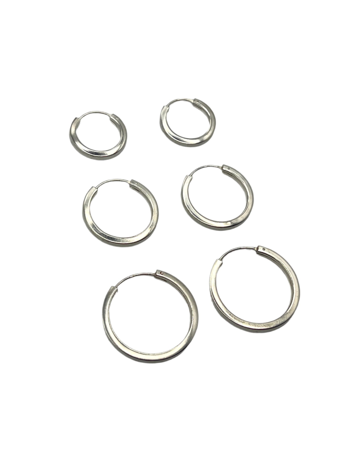 Set of silver hoop earrings on a gray background