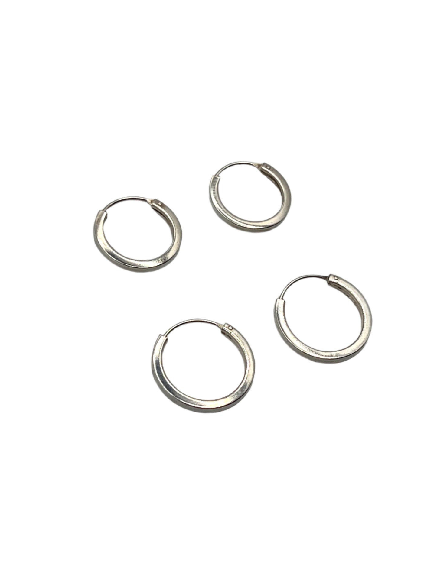 Four silver hoop earrings on a gray background