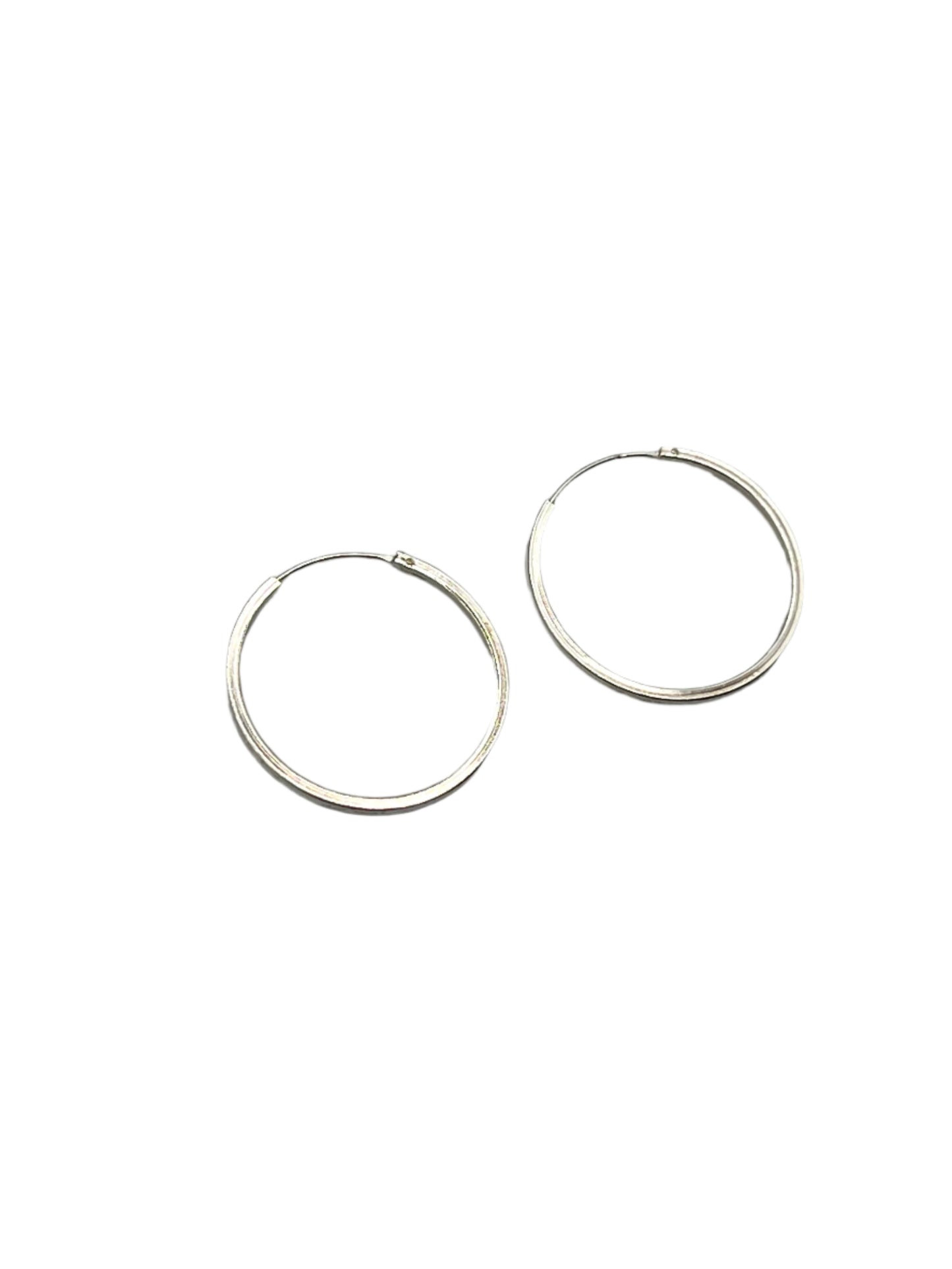Two silver hoop earrings on a gray background