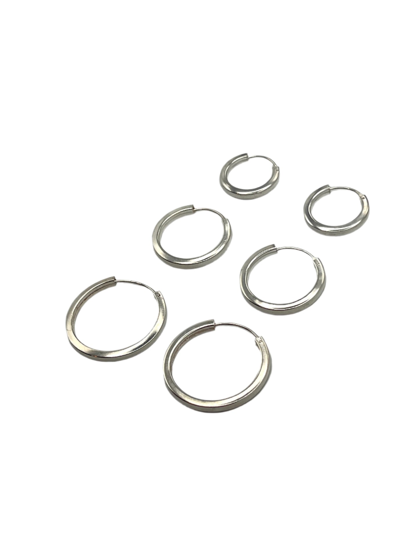 Set of silver hoop earrings on a gray background