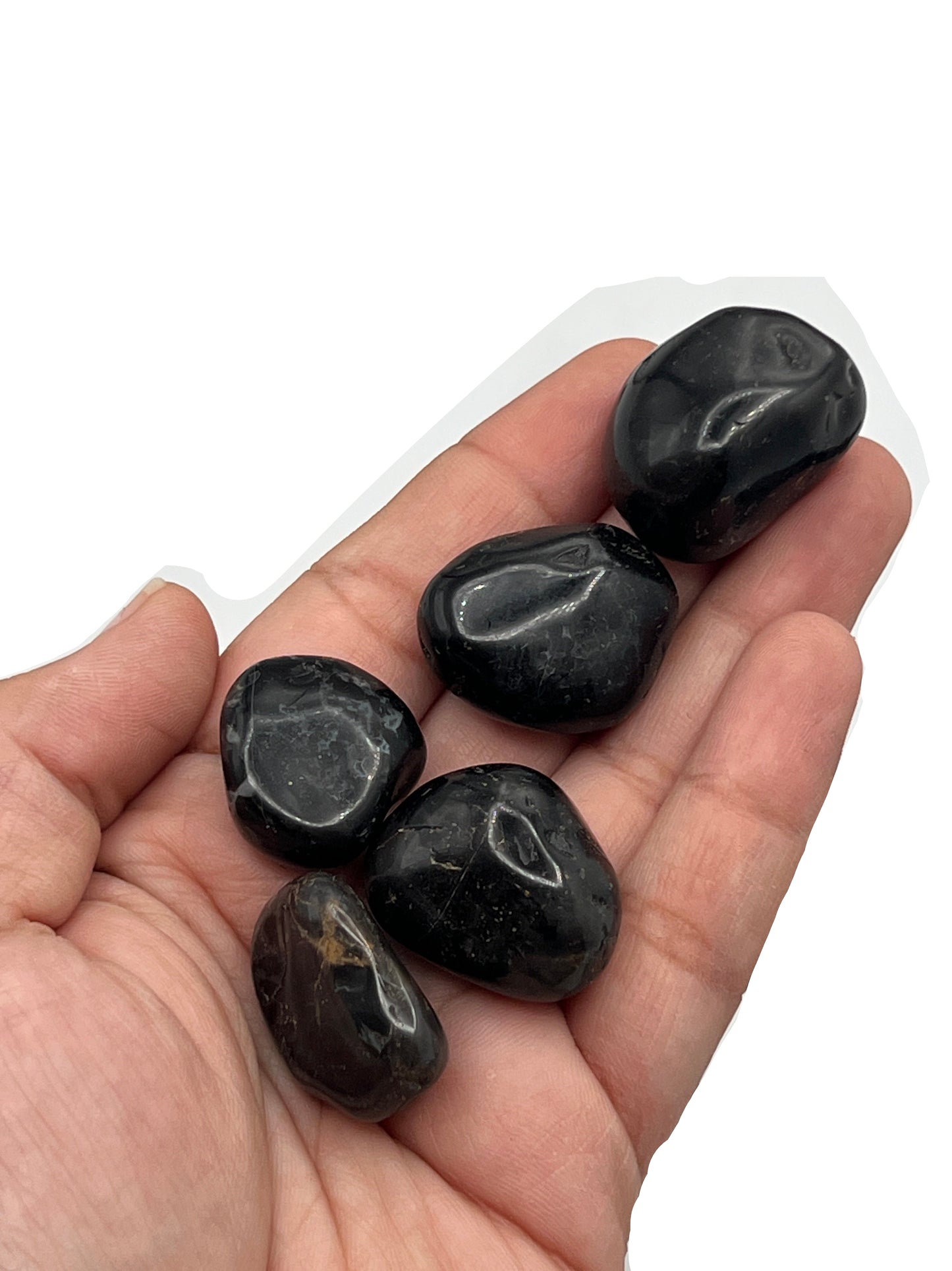 Hand holding several black stones on a white background