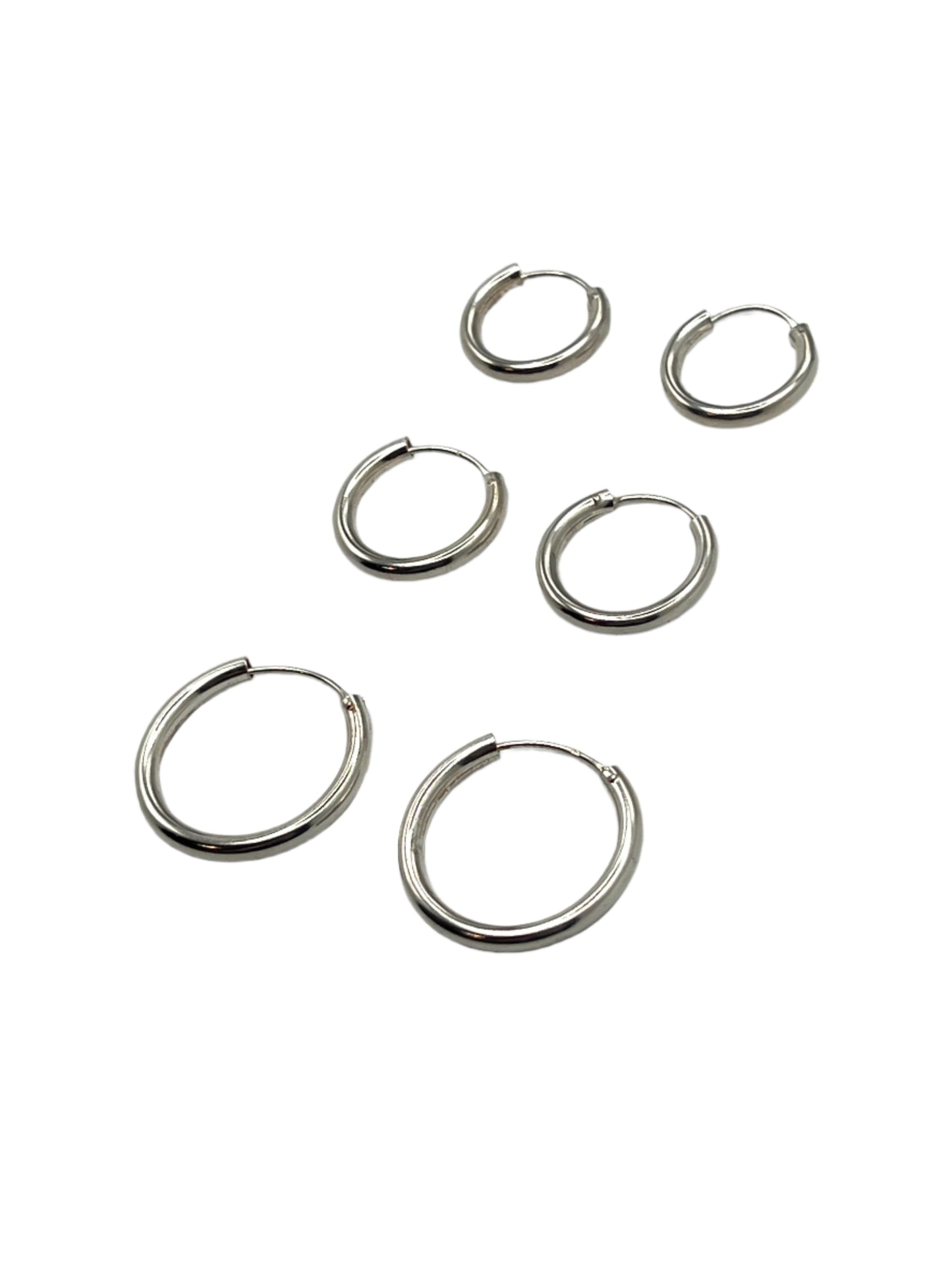 Set of silver hoop earrings on a gray background