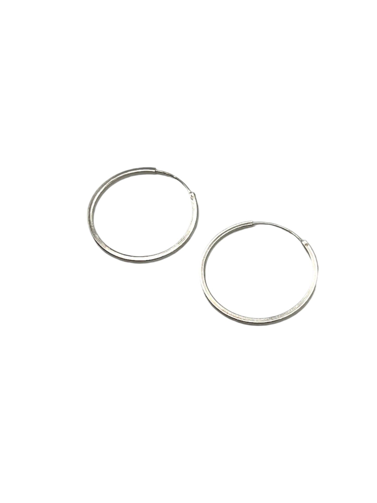 Two silver hoop earrings on a gray background