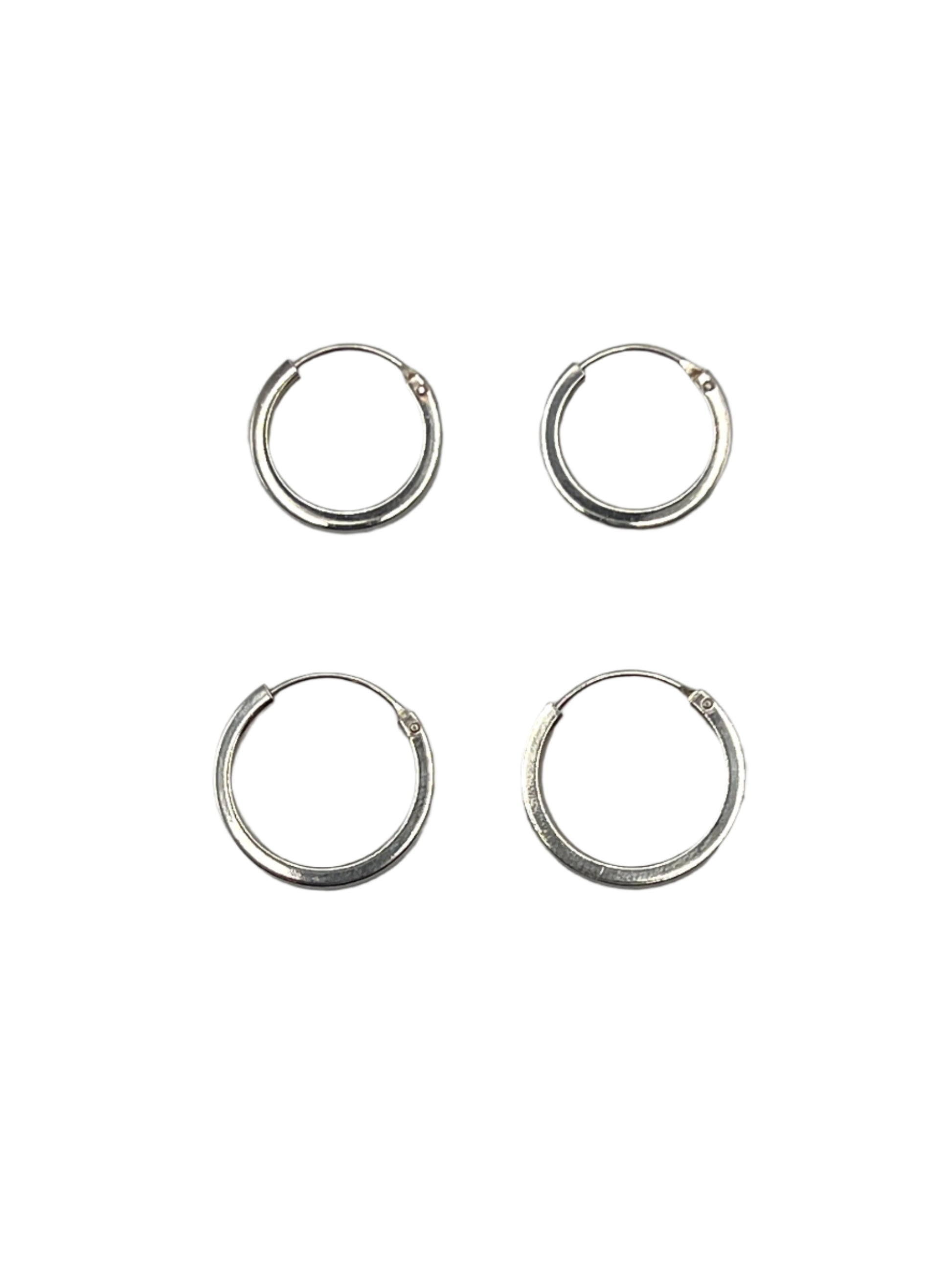 Four silver hoop earrings on a gray background