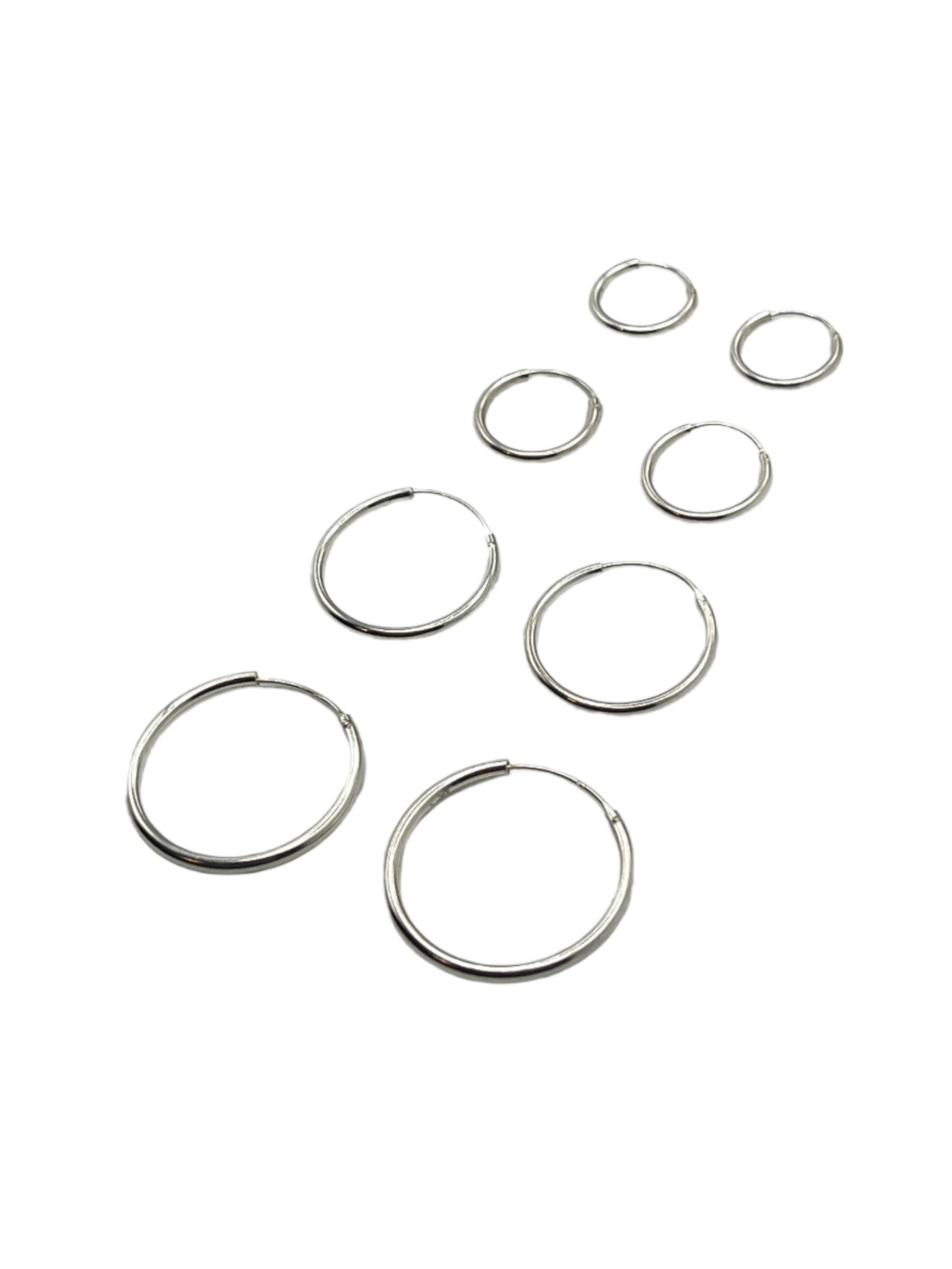 Set of silver hoop earrings on a light gray background