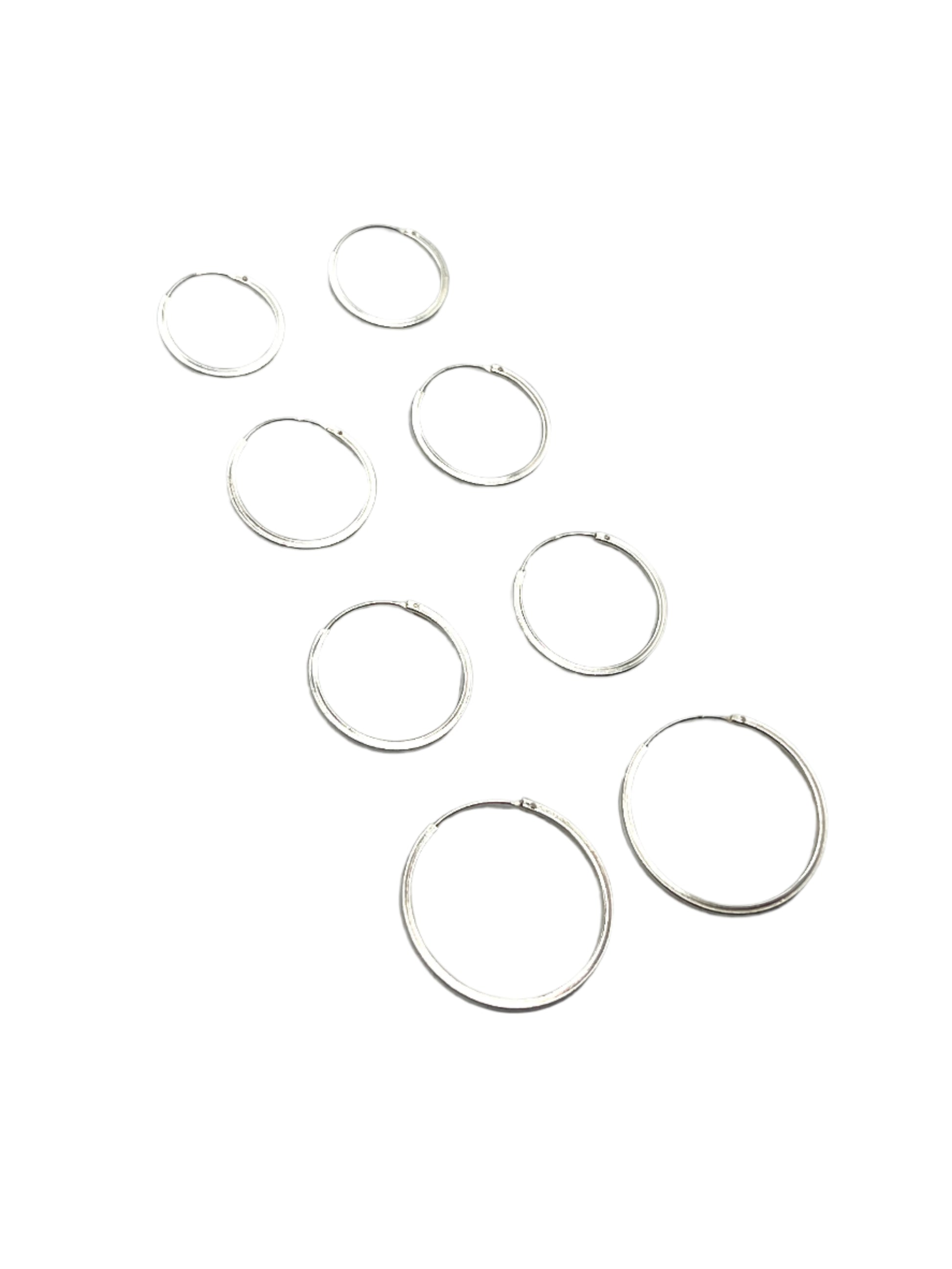 Set of silver hoop earrings on a gray background