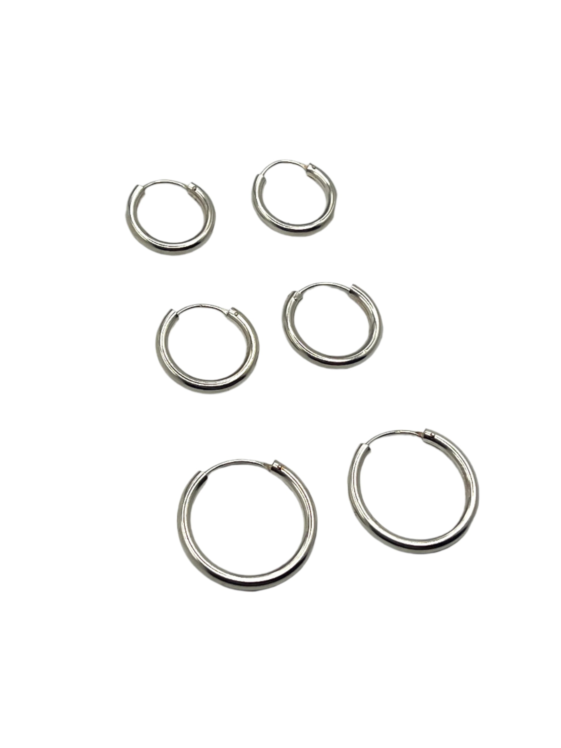 Set of six silver hoop earrings on a light gray background