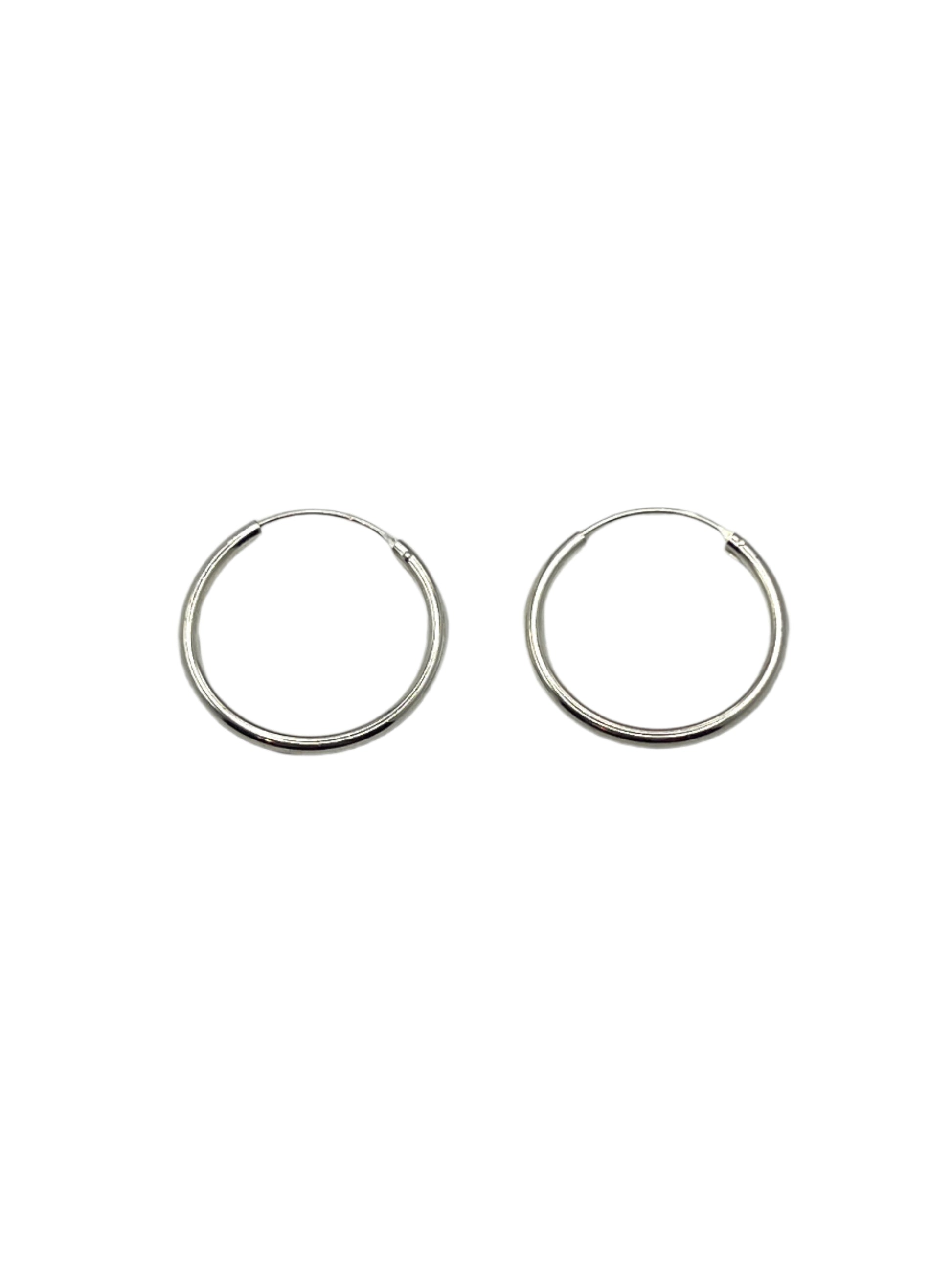 Two silver hoop earrings on a light gray background