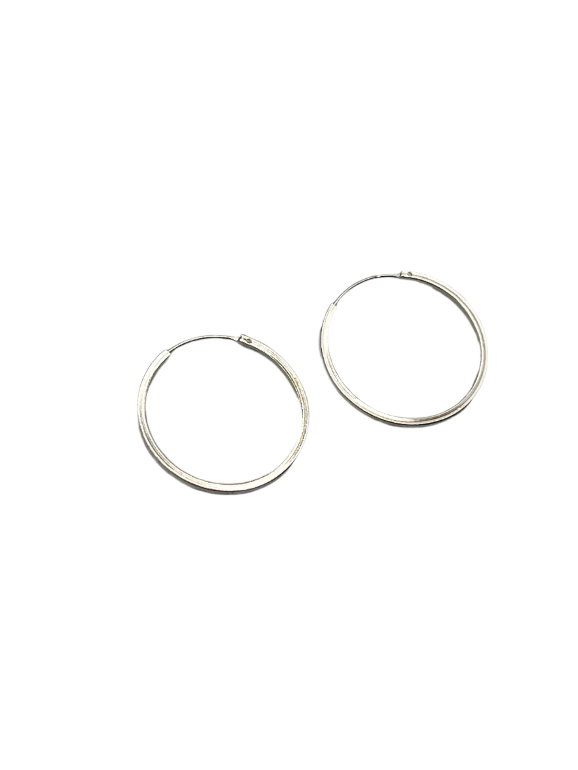 Two silver hoop earrings on a gray background