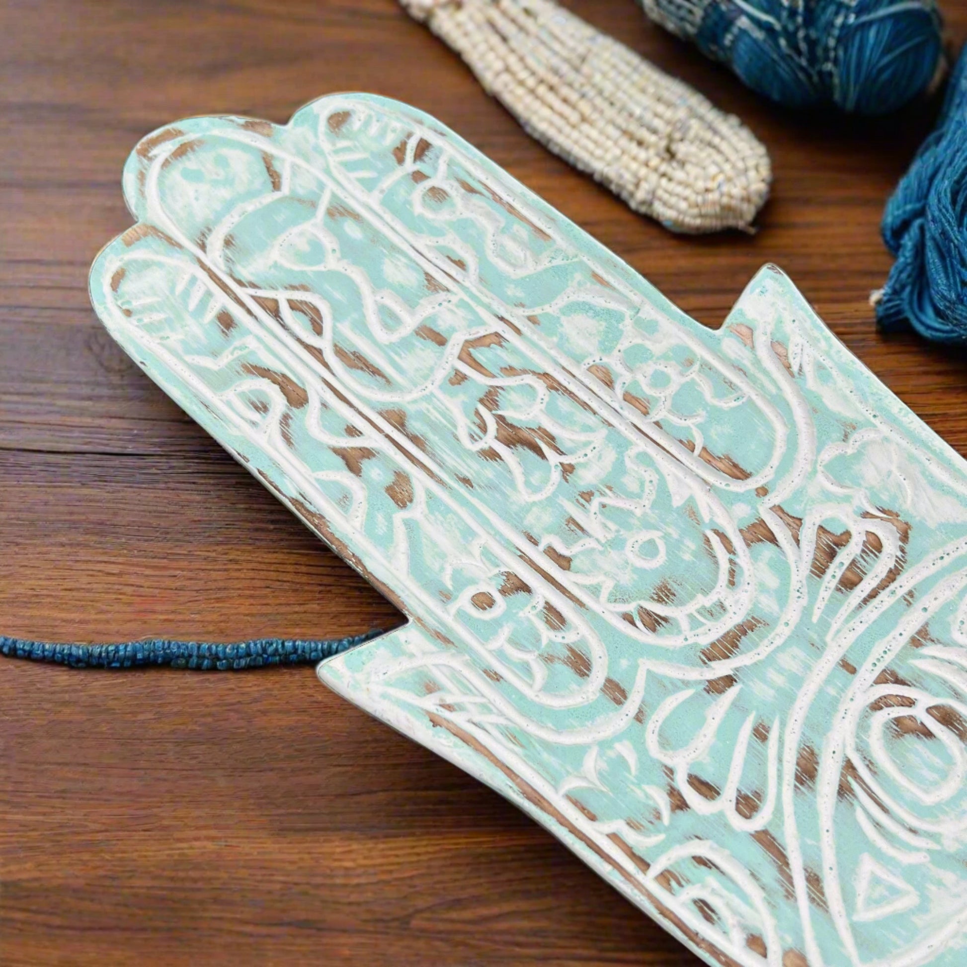 hand carved hamsa hand blue wood plate, upclose hands