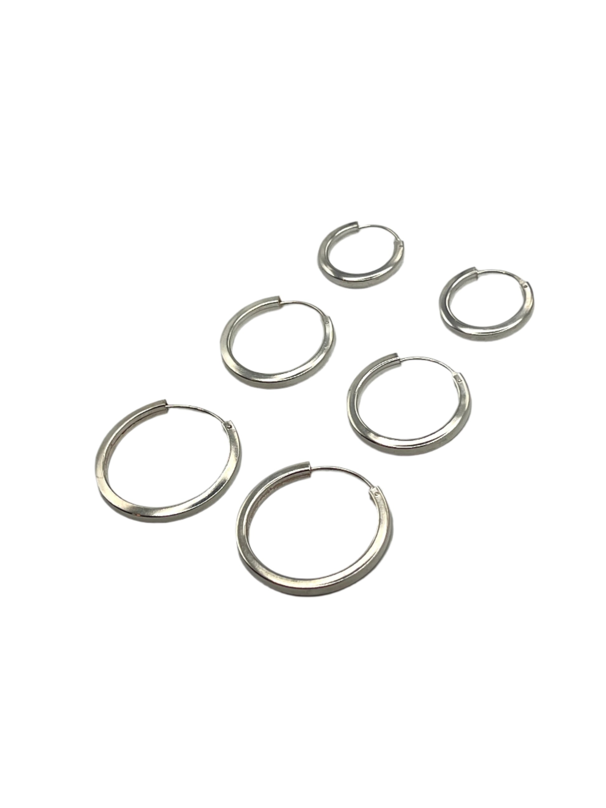 Set of silver hoop earrings on a gray background