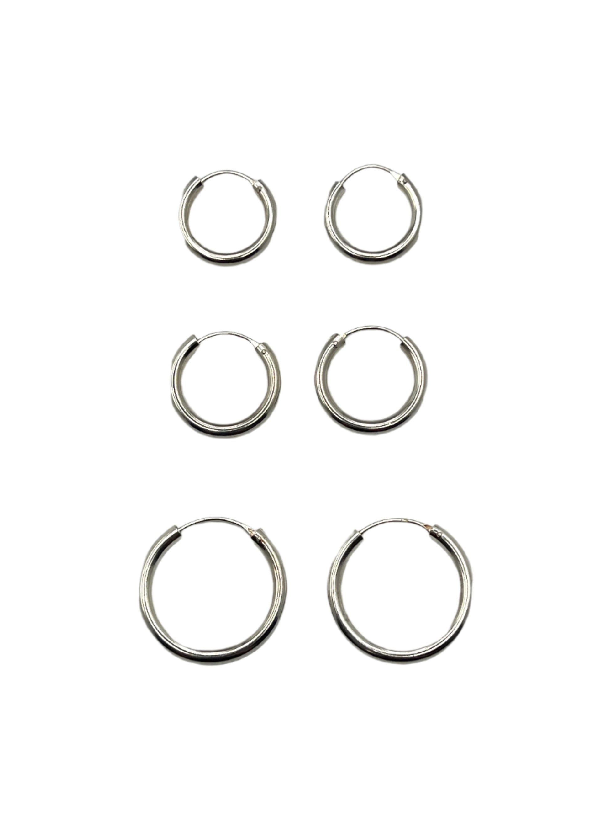 Set of six silver hoop earrings on a gray background