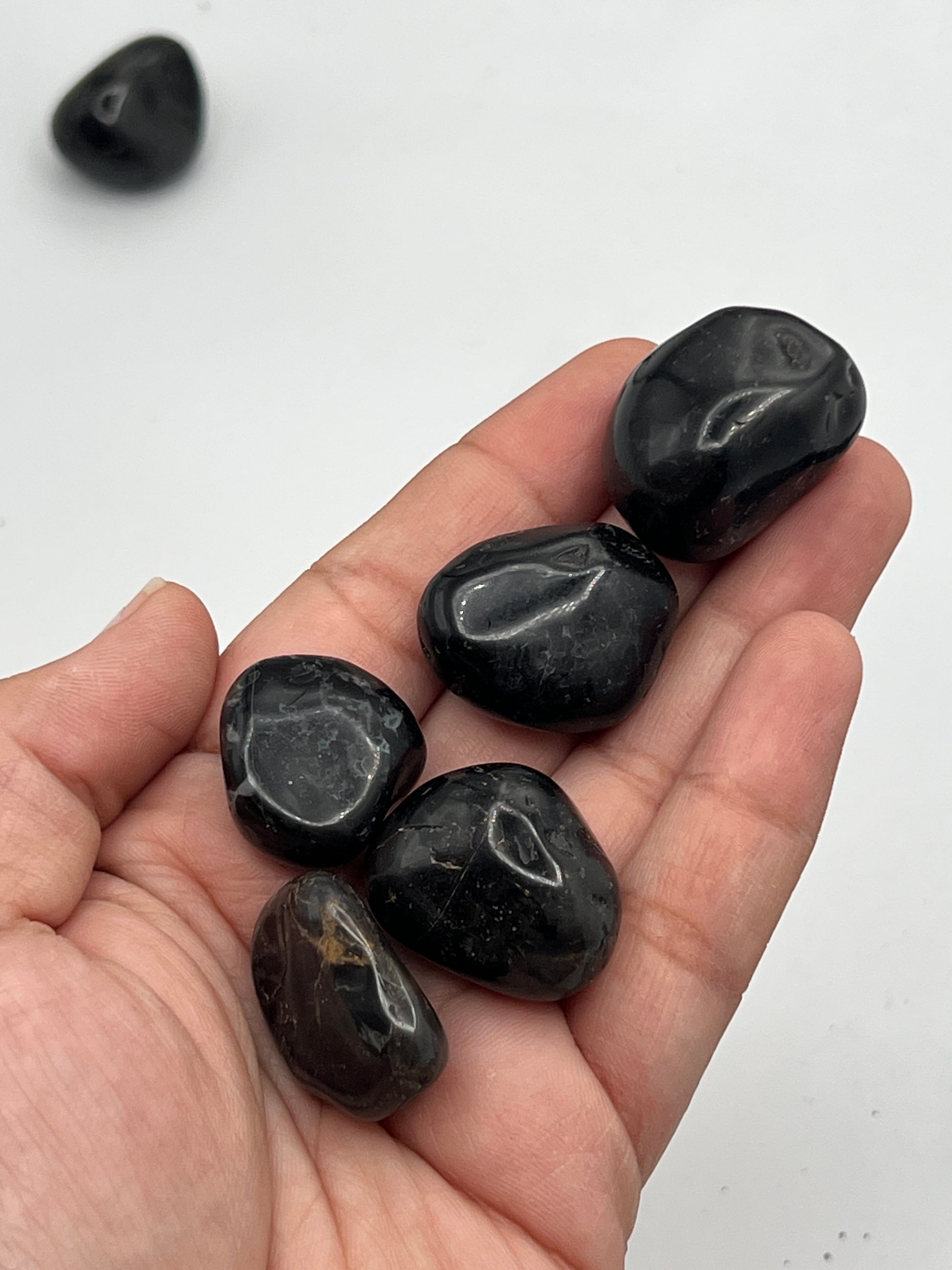 Hand holding several black stones on a white background