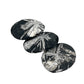 Three black stones with white floral patterns on a white background