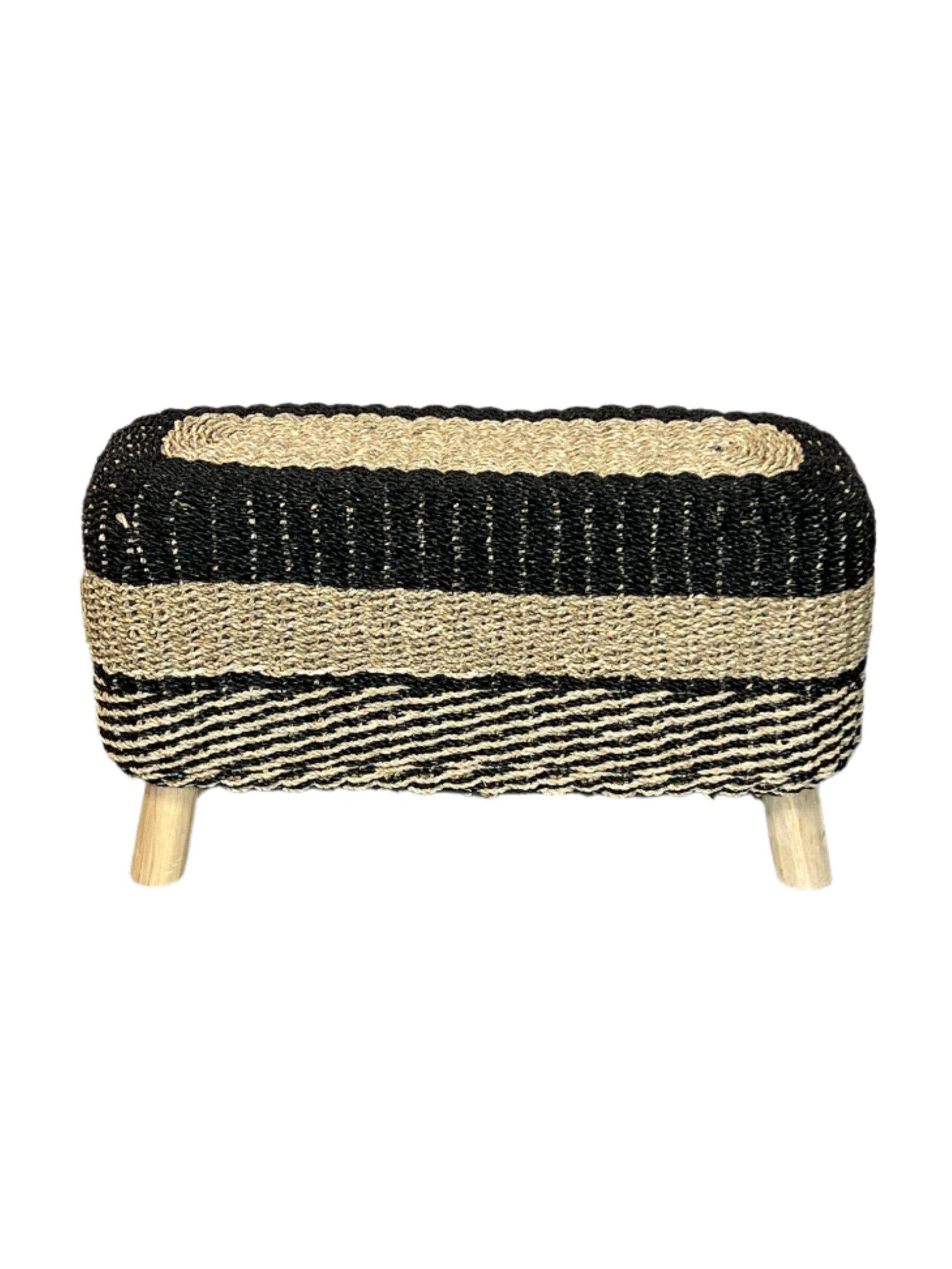 A handcrafted seagrass accent bench with black and brown stripes and wooden legs.