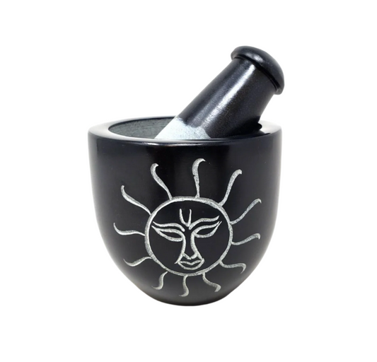 Black soapstone mortar and pestle with sun design on a white background