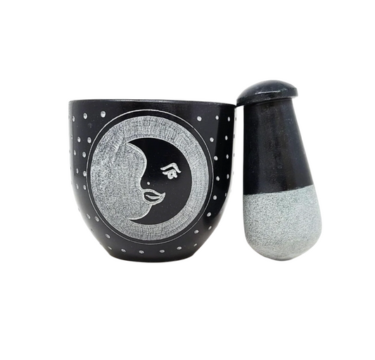 Black mortar and pestle with moon and face design on a white background