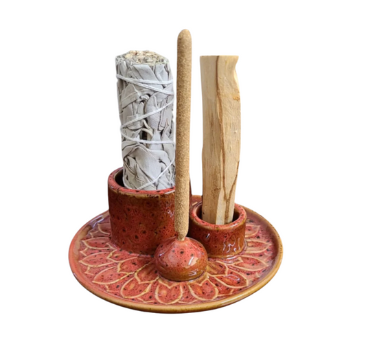 Ceramic holder with incense sticks and a smoke roller on a decorative plate.